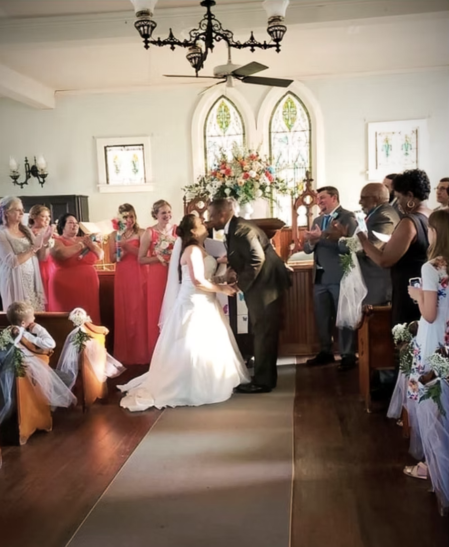 First kiss at the Village Chapel altar with stained glass behind