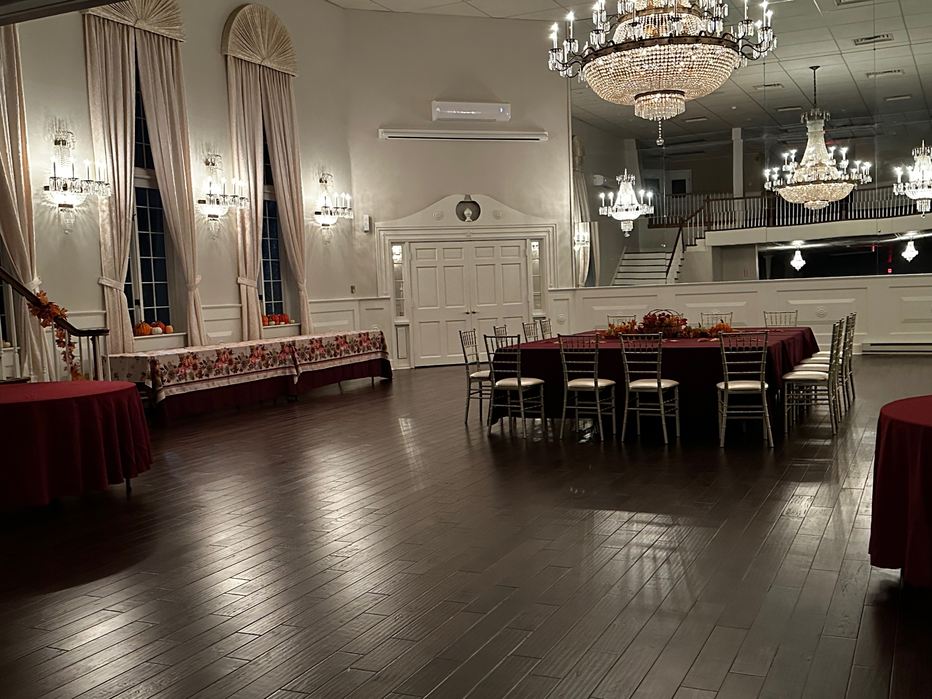 A private dining room set for a rehearsal dinner beneath chandeliers