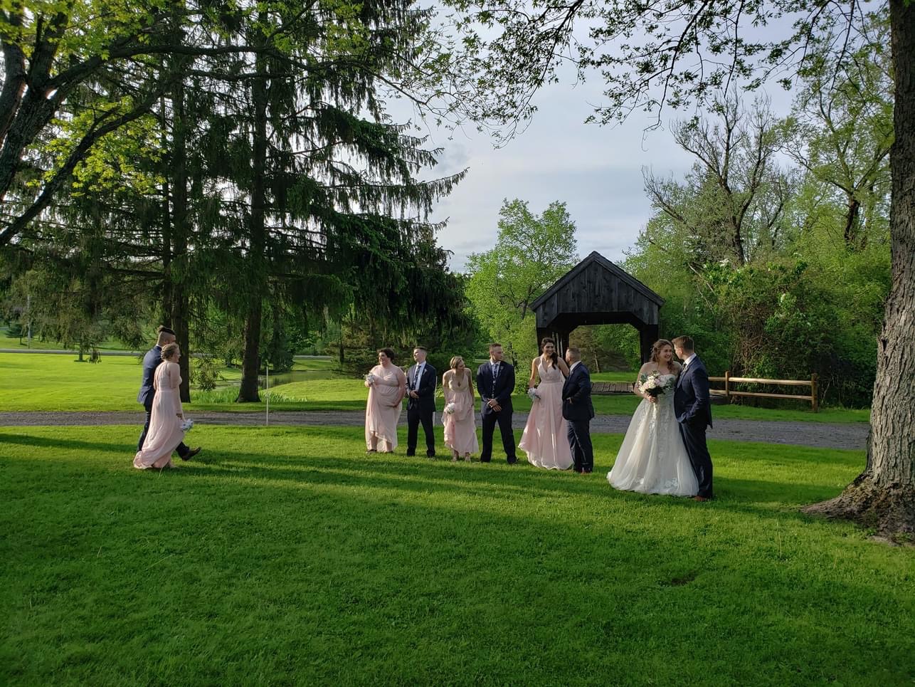 A wedding party gathers at the covered bridge at Americana Village